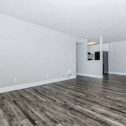 View of living room with plank flooring, dining area and kitchen at Stone Canyon Apartments, located in Colorado Springs, CO