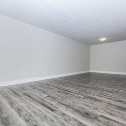 View of living room with plank flooring, dining area and kitchen at Stone Canyon Apartments, located in Colorado Springs, CO