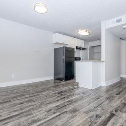 View of living room with plank flooring, dining area and kitchen at Stone Canyon Apartments, located in Colorado Springs, CO