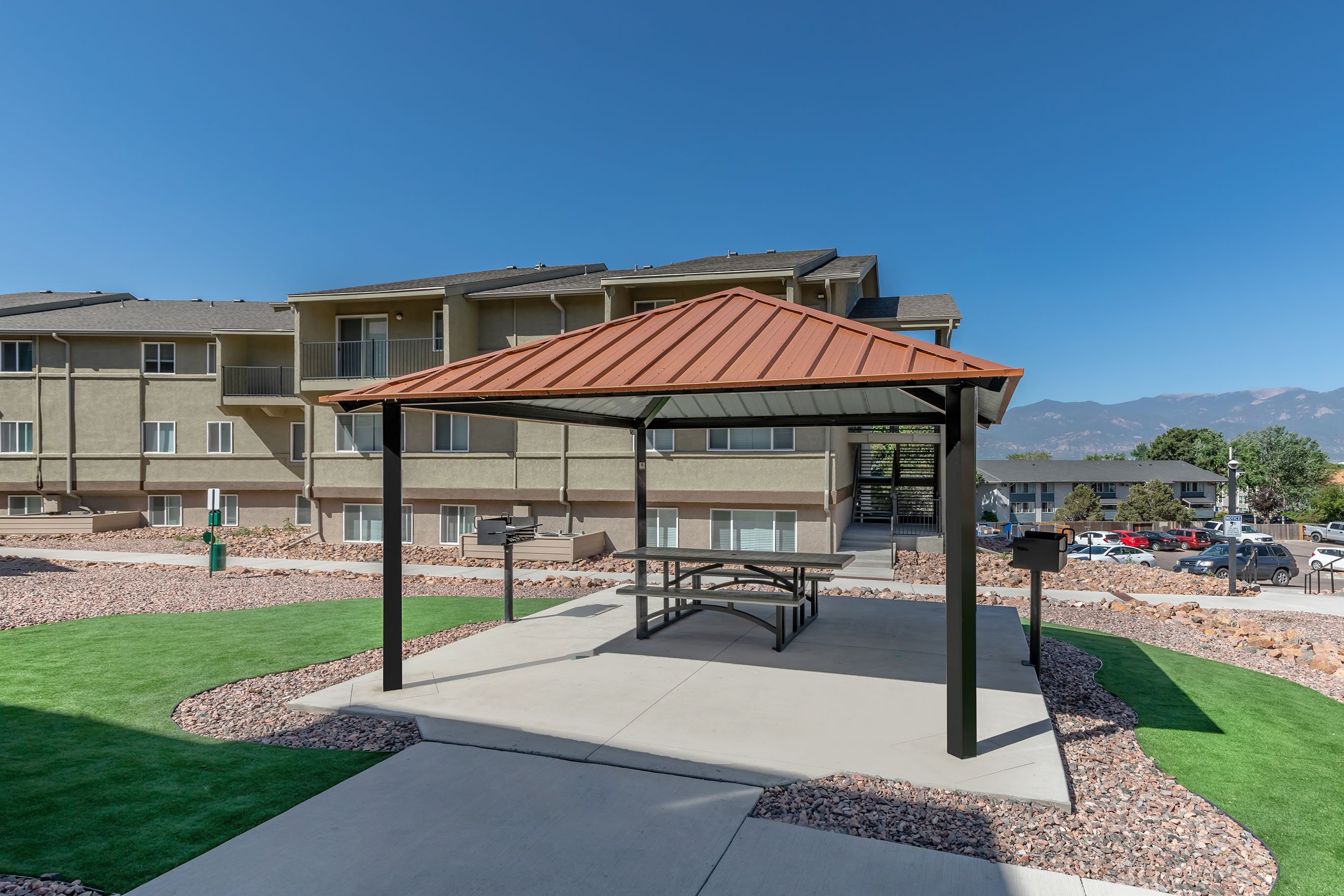 Outdoor dining area and charcoal grill covered by a pergola